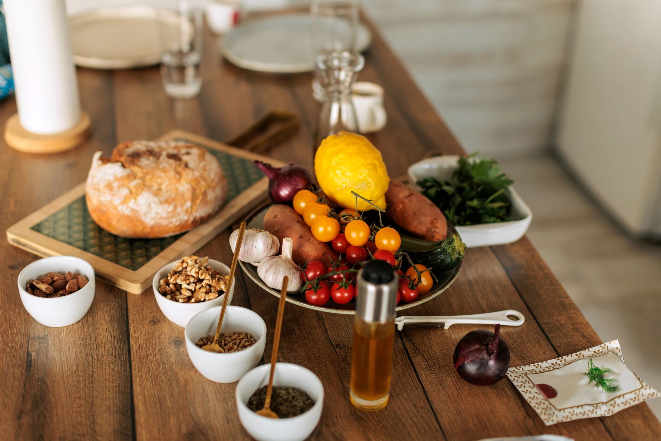 Fresh Vegetables, Nuts, Bread and Olive Oil on Rustic Wooden Table